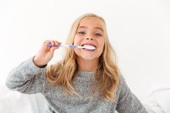 close-up-portrait-cute-kid-gray-pajamas-brushing-her-teeth_171337-10348